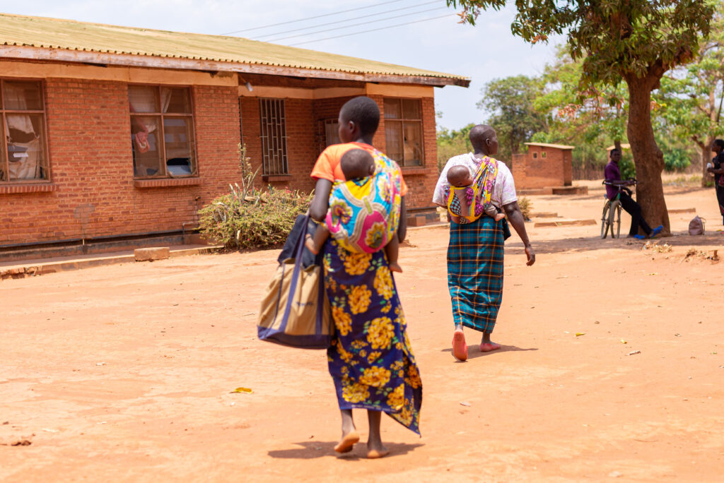 Women walking and carrying babies in a village in Malawi