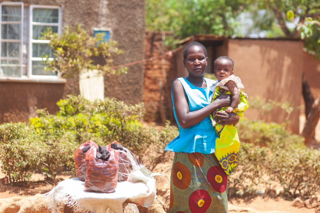 A young woman holds a baby in a village in Malawi